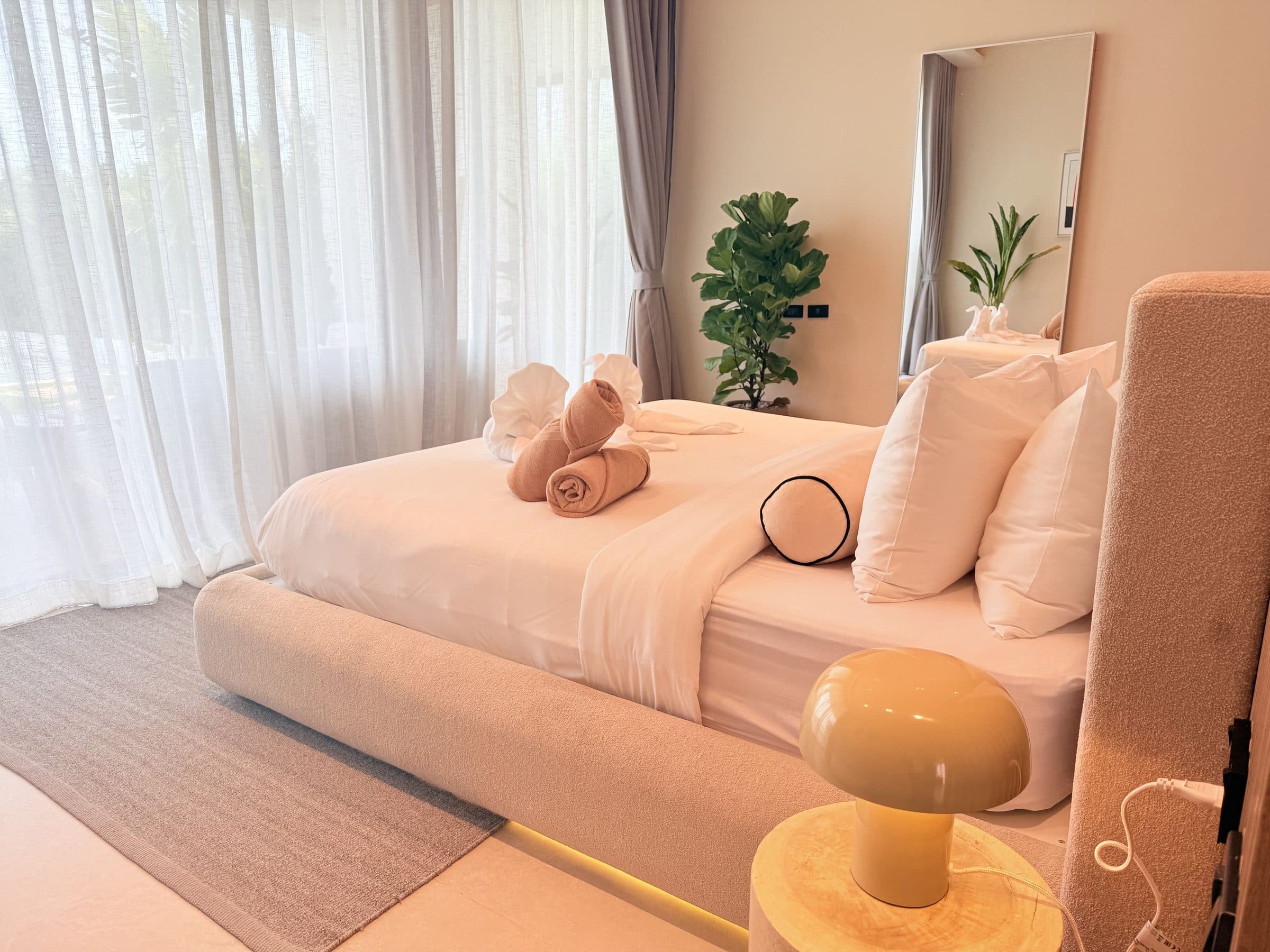 Bright bedroom with sheer curtains and fresh towels