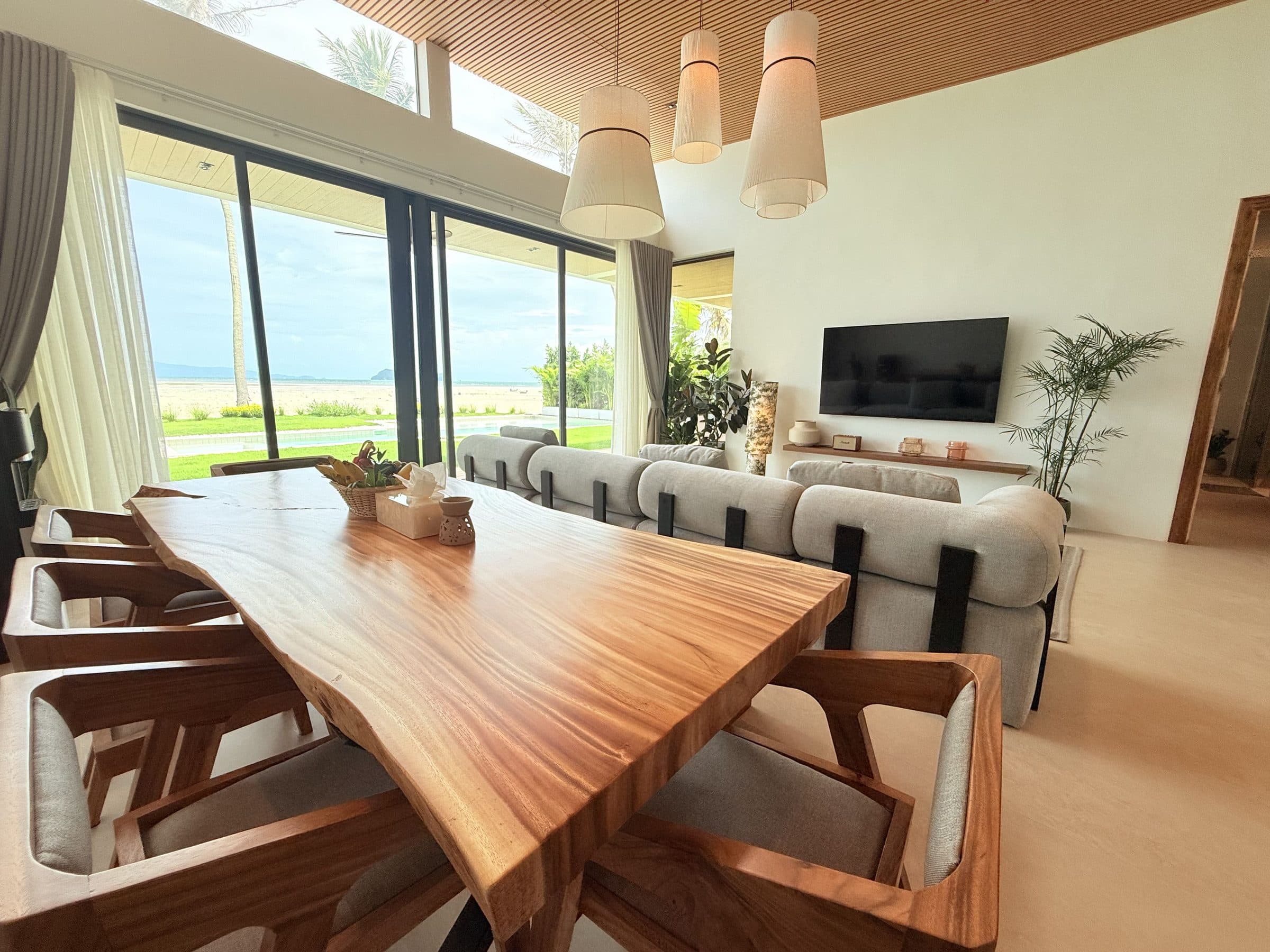 Open-plan living and dining room with the sea through floor-to-ceiling glass