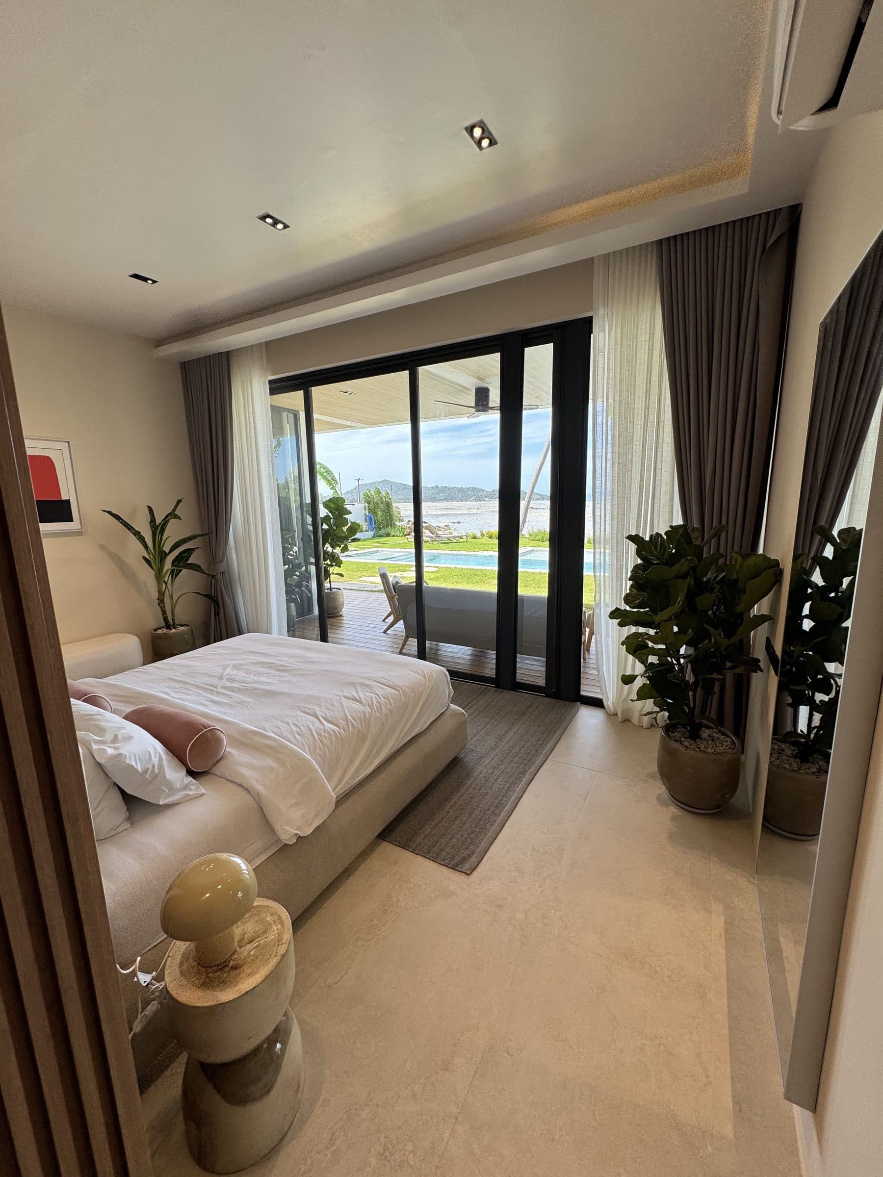 Master bedroom looking out through glass doors to the garden and the sea